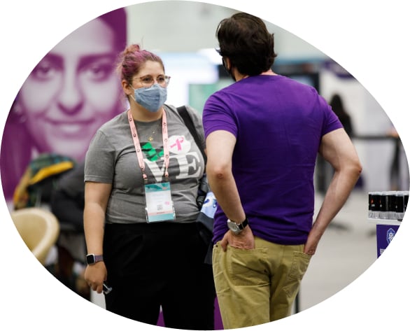 Man talking to woman with masks on at conference