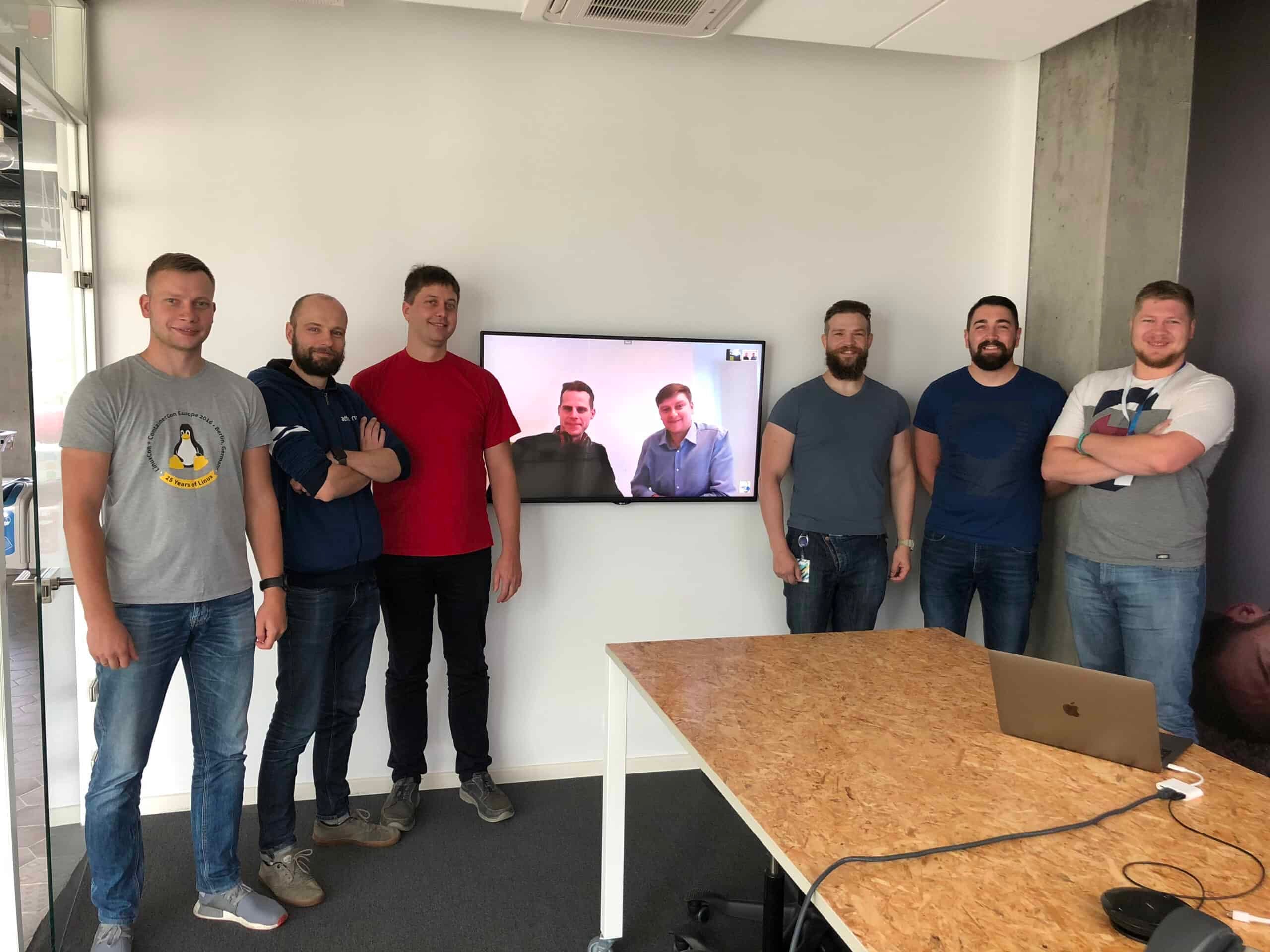 Gentlemen in an office with a screen monitor showing two gentlemen on video call