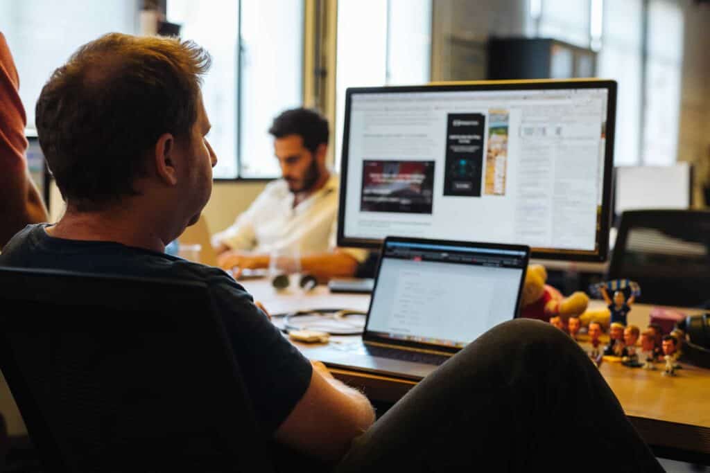 A gentleman working with a screen monitor and a laptop