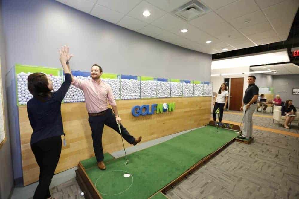 A lady and gentleman sharing high five on a mini golf carpet at GolfNow