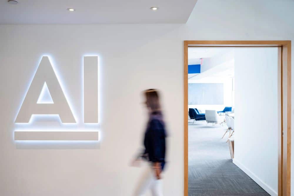 A lady walking passing by a door with AI wording on the wall