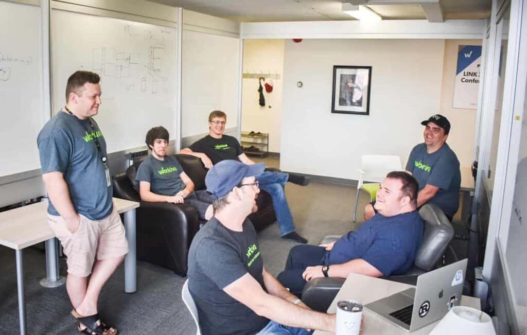 Six gentlemen with Workiva t-shirts talking in an office