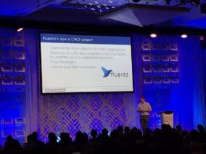 A gentleman speaks on stage in CloudnativeCon + KubeCon about Fluentd is now a CNCF Project