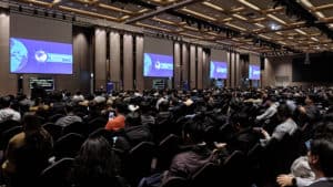 Participants in conference hall sitting and paying attention to the presentation on stage