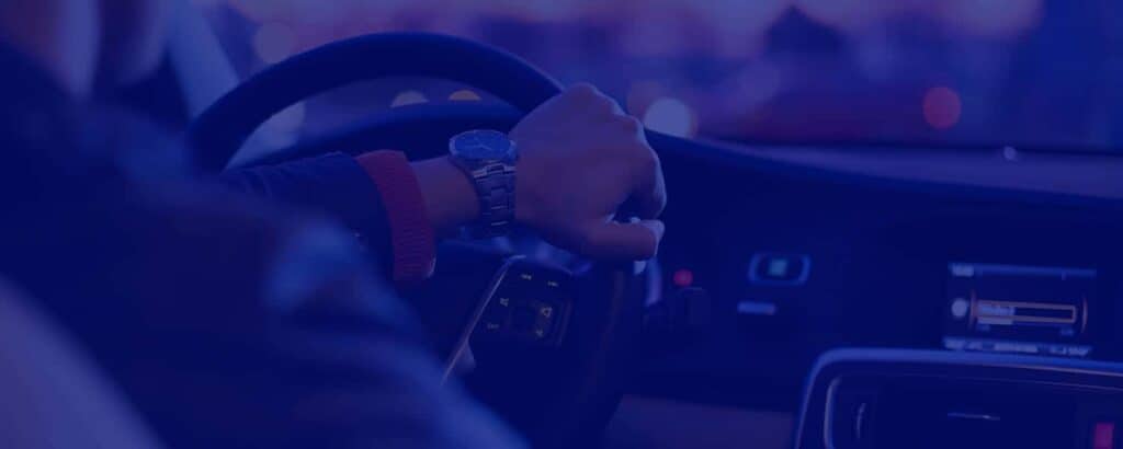 A gentleman wearing watch controlling a car steering wheel