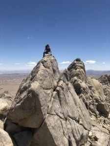 Kris Nova sitting on a big rock enjoying the mountain view