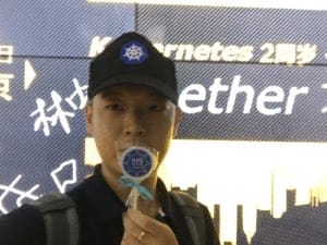 A gentleman holding k8s lollipops and wearing CNCF hat