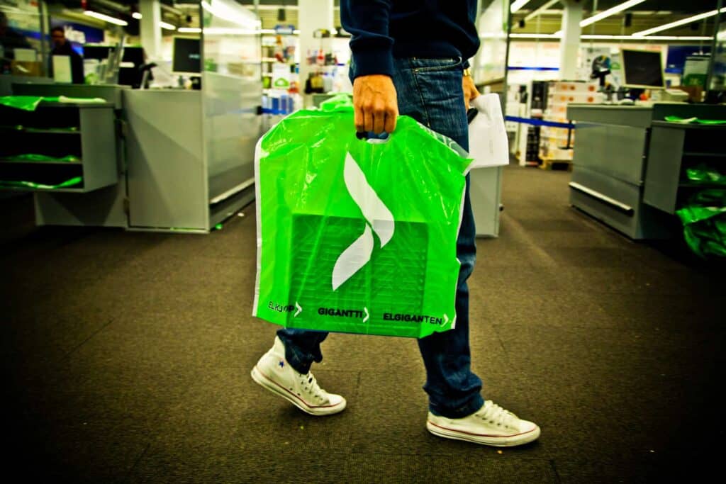 A person carrying green plastic bag with Elkjøp logo