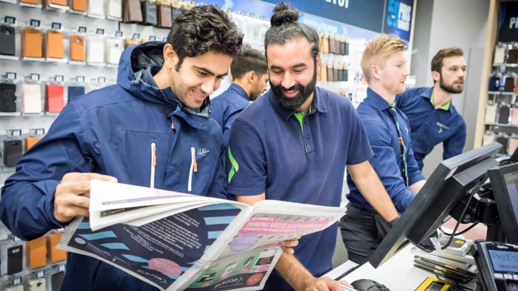 A gentleman happily sharing news on newspaper to Elkjøp staff at store