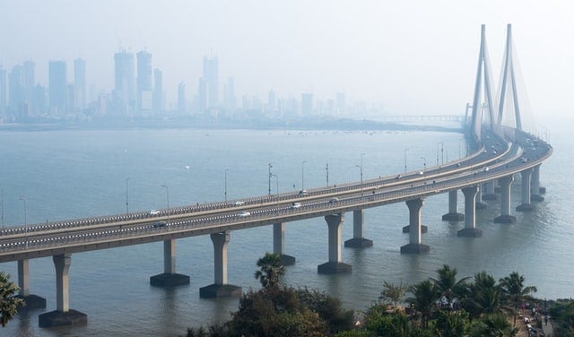 Big bridge with cars going across a bay with city in the background