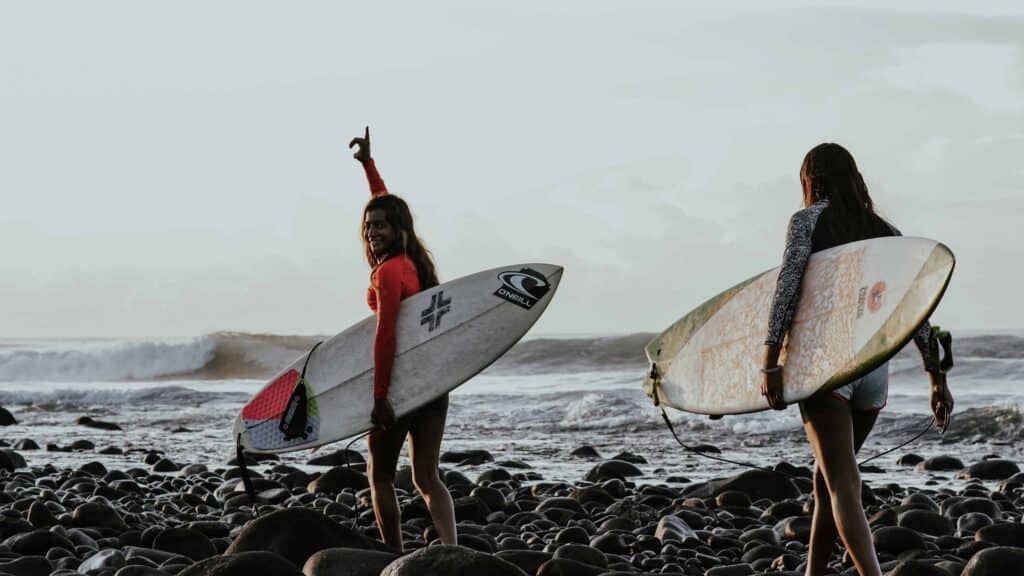 Two surfers walking to the sea carrying surfboard