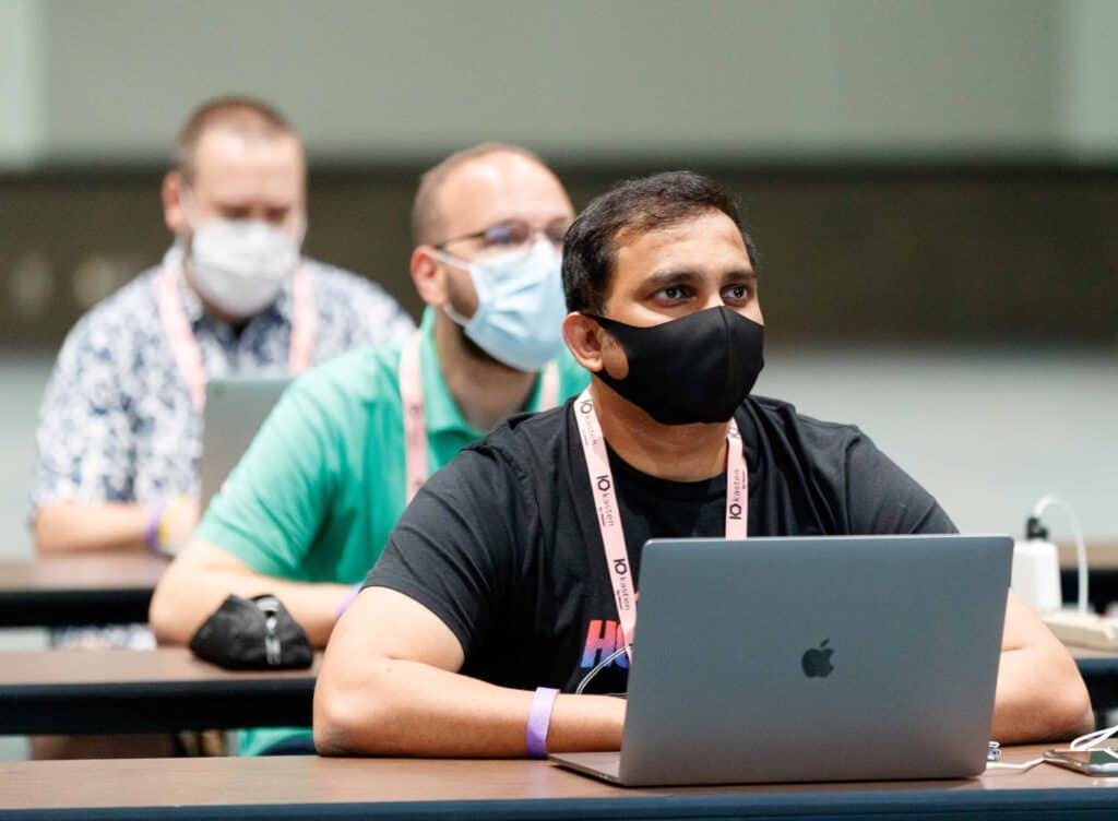Men at conference listening to talk with laptops