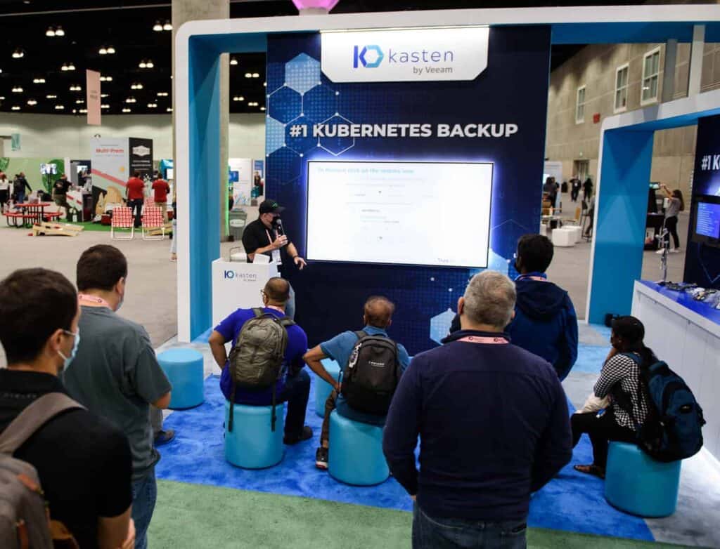 People watching a presentation at a conference sponsor booth