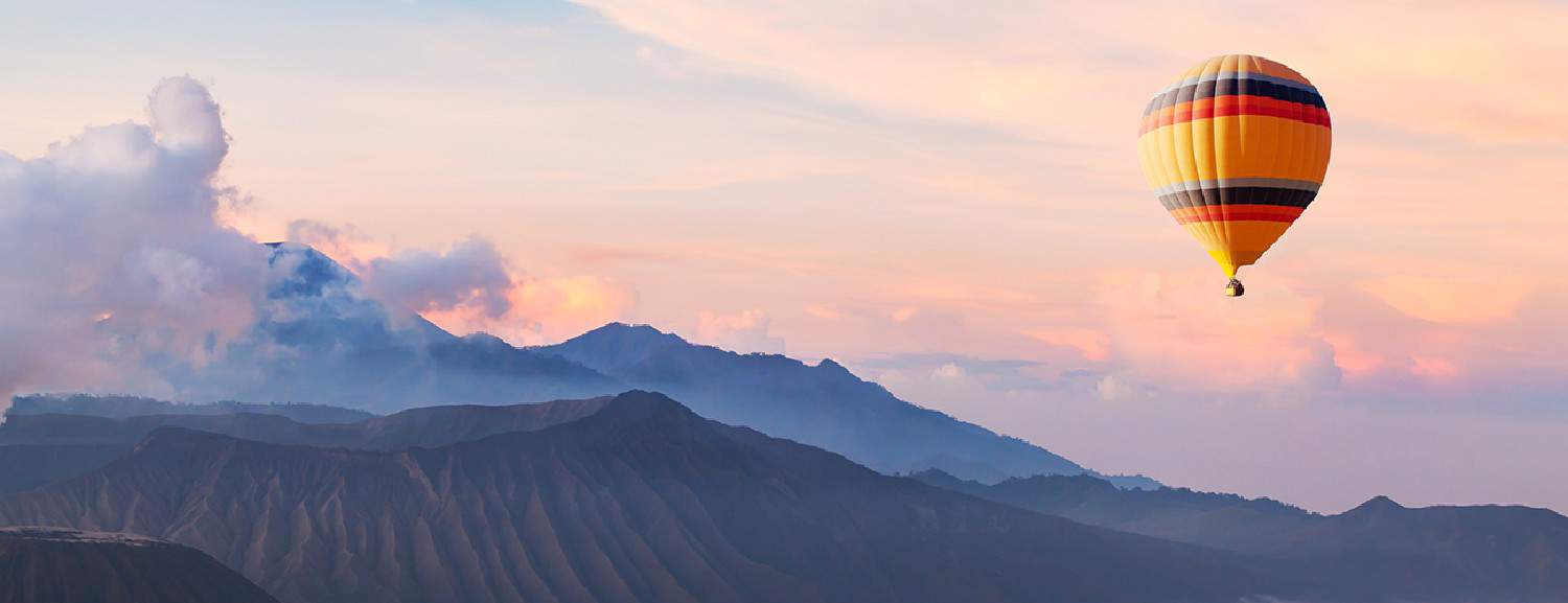 Hot air balloon flying across the mountain