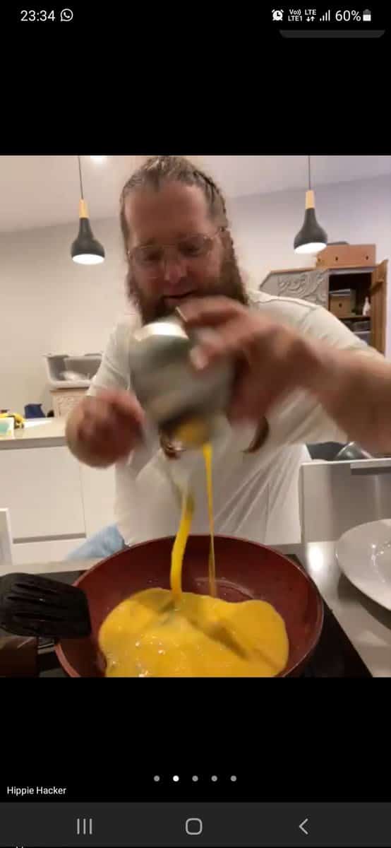 Screenshot from a video chat showing a guy in glasses pouring the egg mixture to a heated pan
