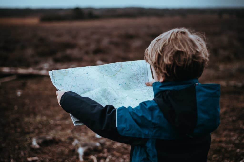 A boy in blue jacket holding and looking at the map
