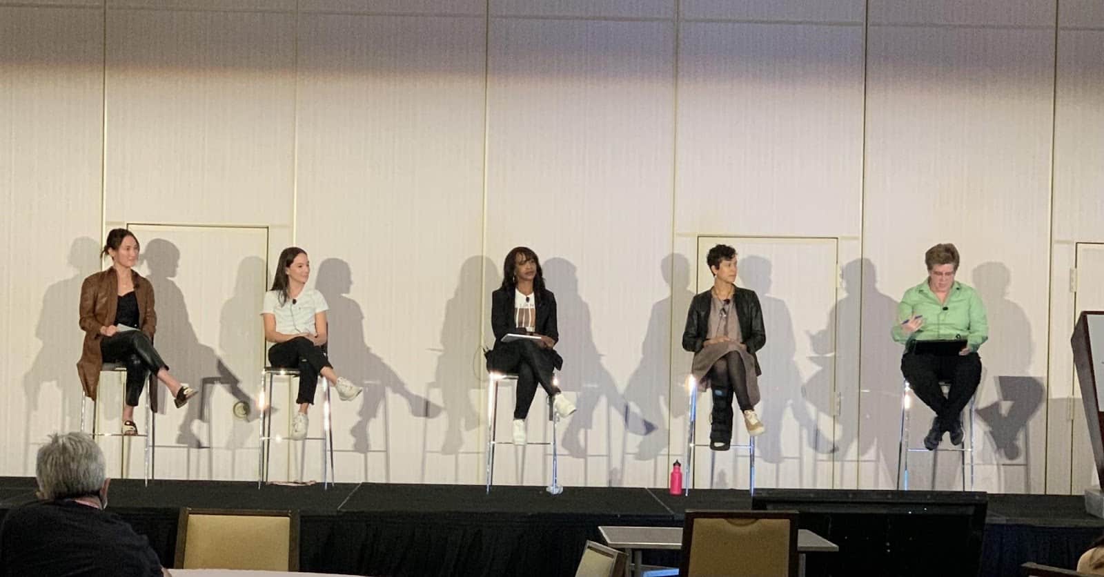 Five smart casual dressed ladies sitting on stage as speakers on a discussion panel