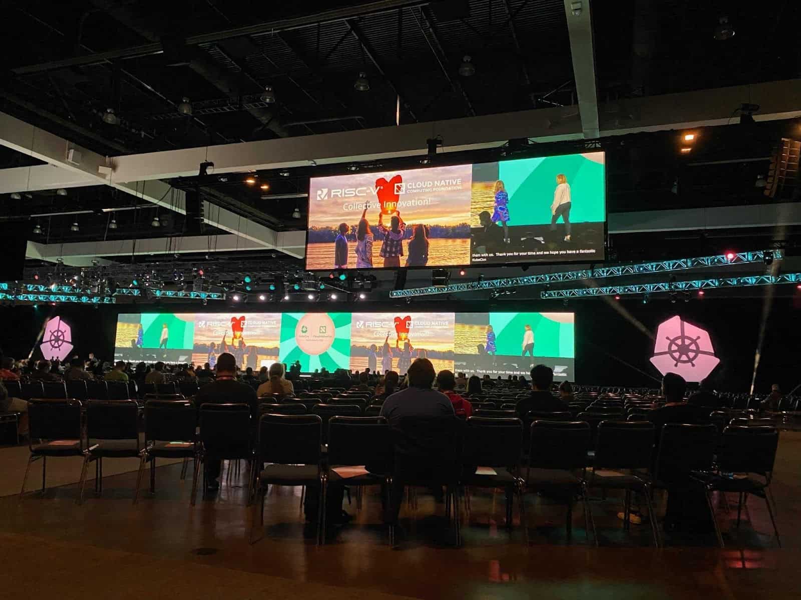 Participants sitting in a conference hall, looking at screen projectors