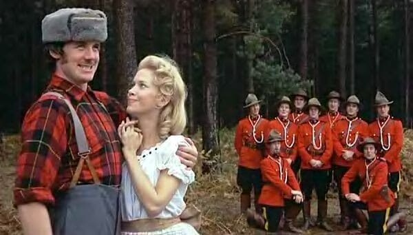 Group of soldiers standing apart, smiling and staring at the lumberjack holding his lady closely