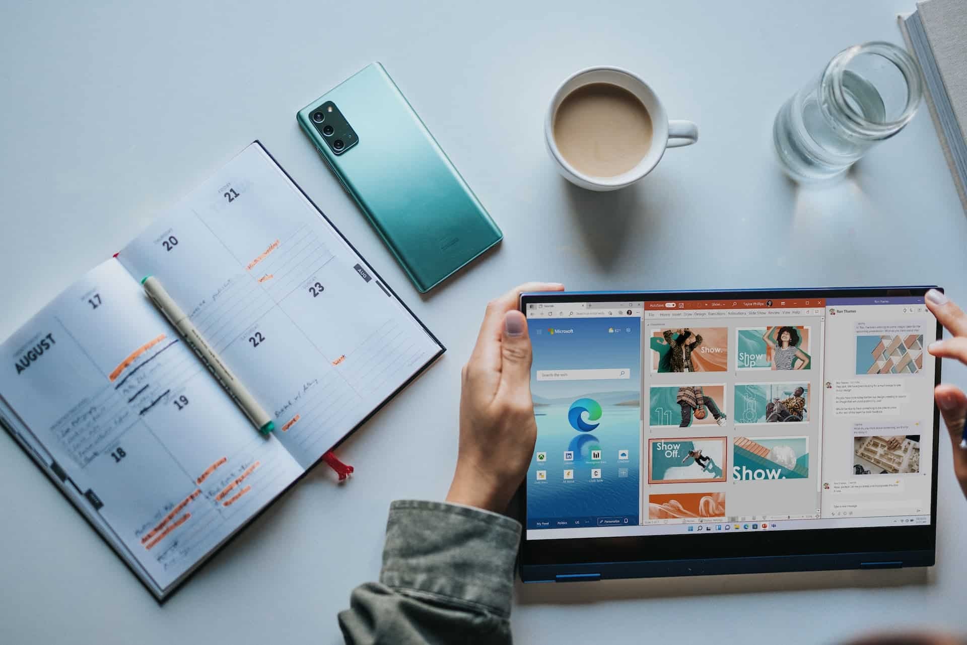 Table with tablet running microsoft windows, a calendar open at August and a cup of coffee