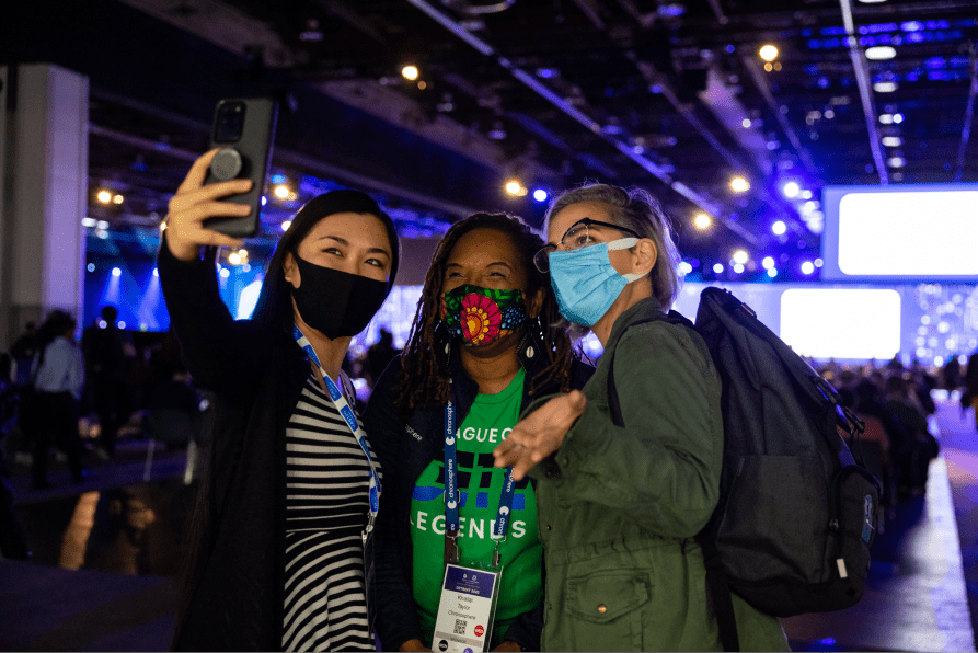 Three ladies in masks taking selfie in KubeCon + CloudNativeCon North America 2022 event hall