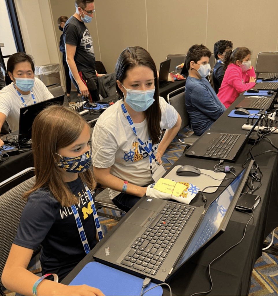 A girl with the laptop guided by a lady in a classroom