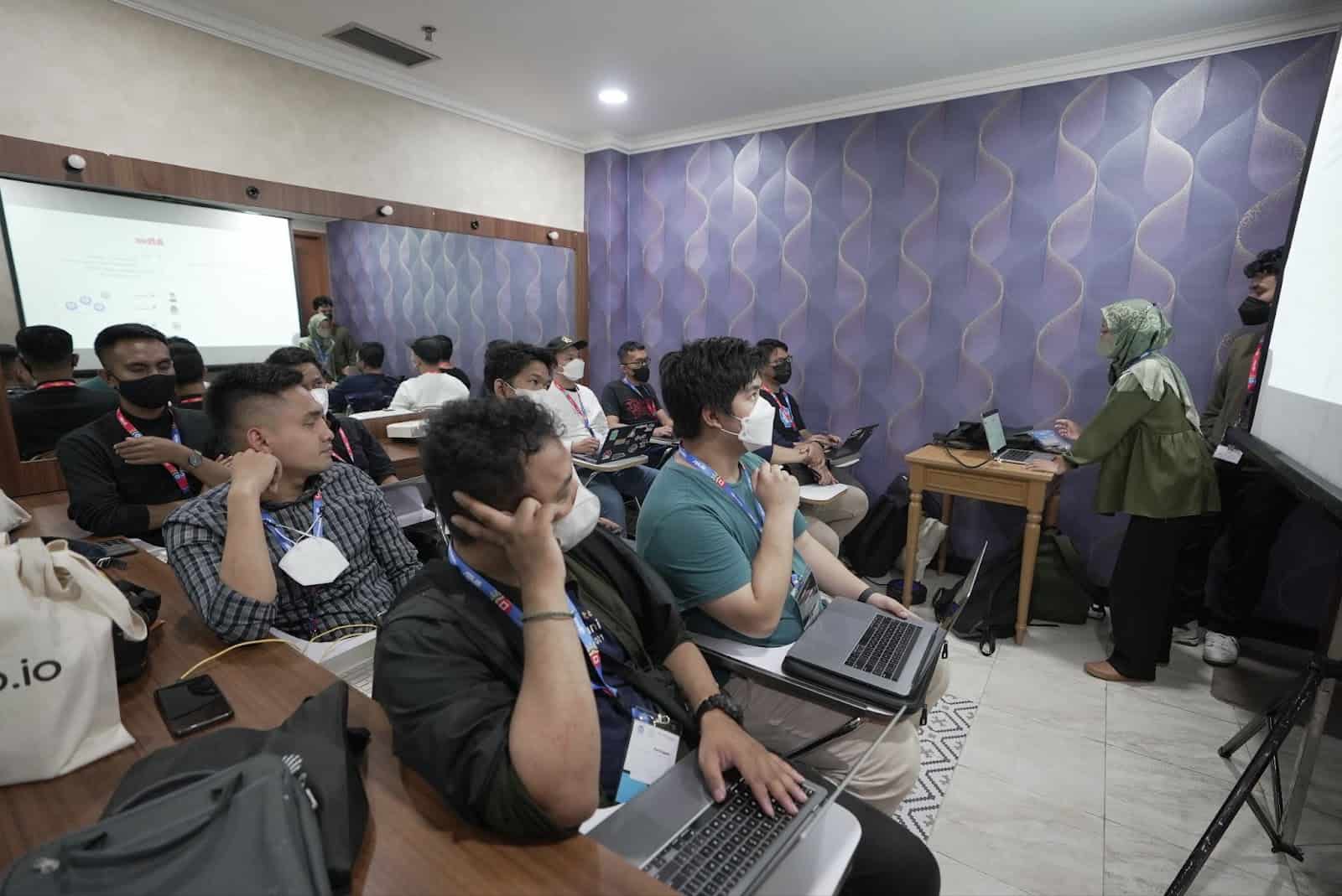 A lady giving presentation in front of gentlemen with computers