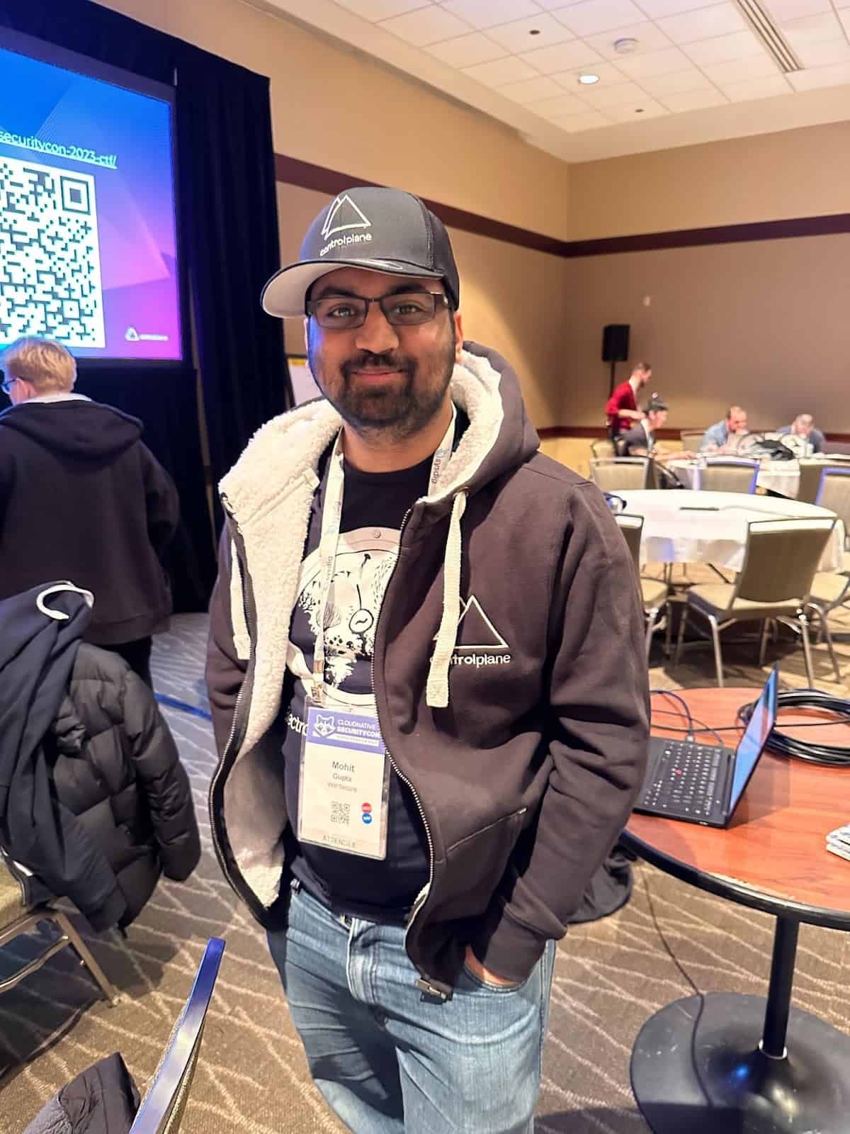 A gentleman in glasses and hat posing for picture in the conference room