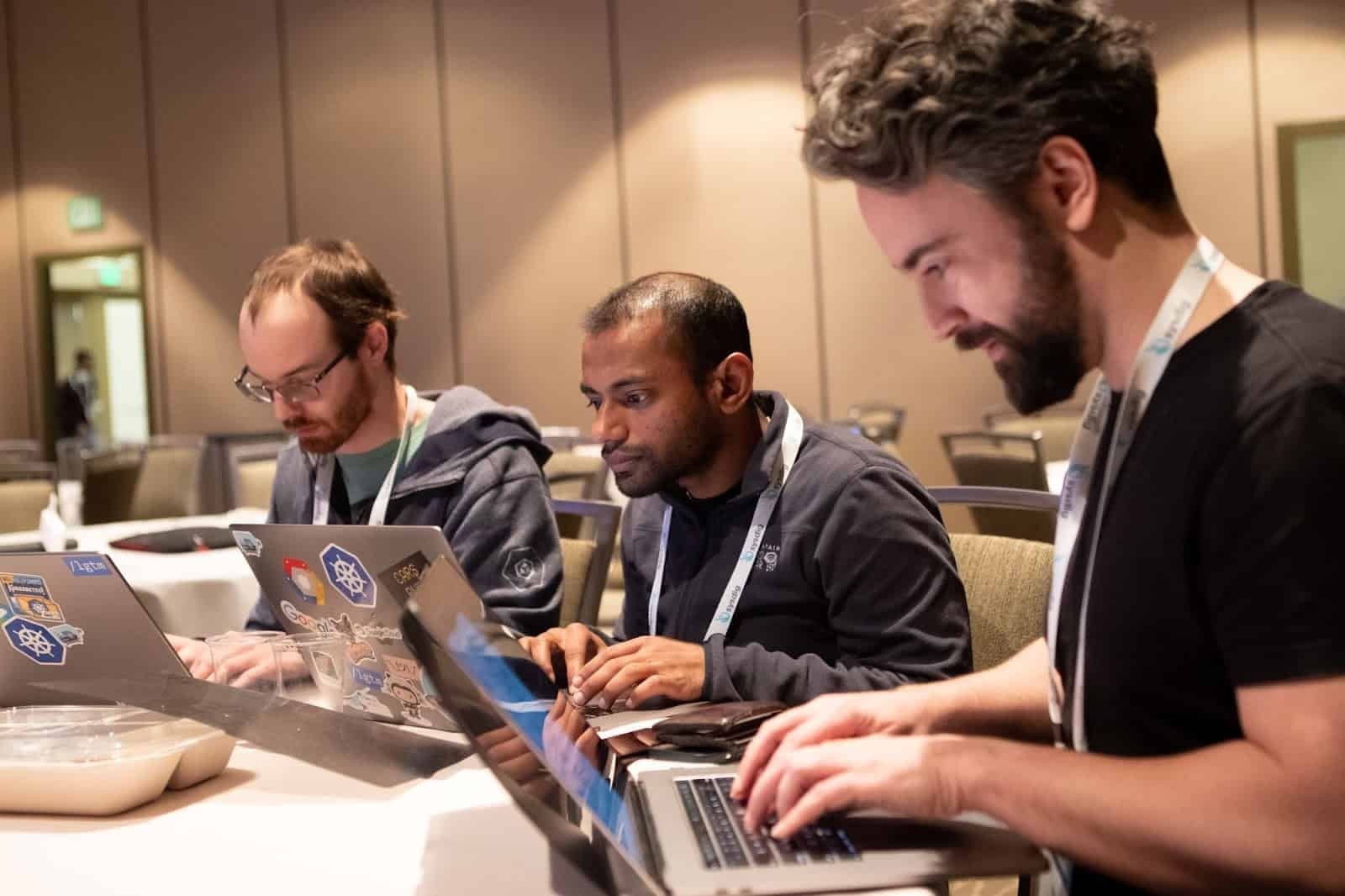 Three gentlemen working in their computers in the conference hall