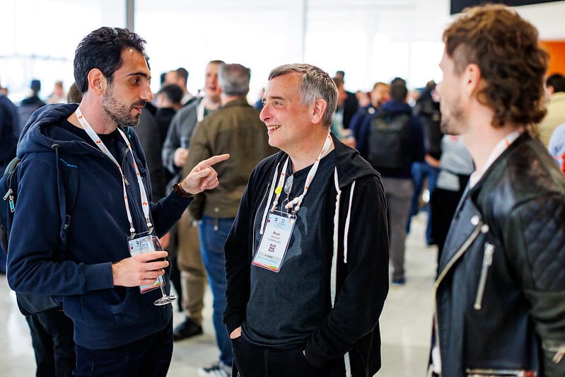 A gentleman holding wine glass having conversation with two other gentlemen in the event hall