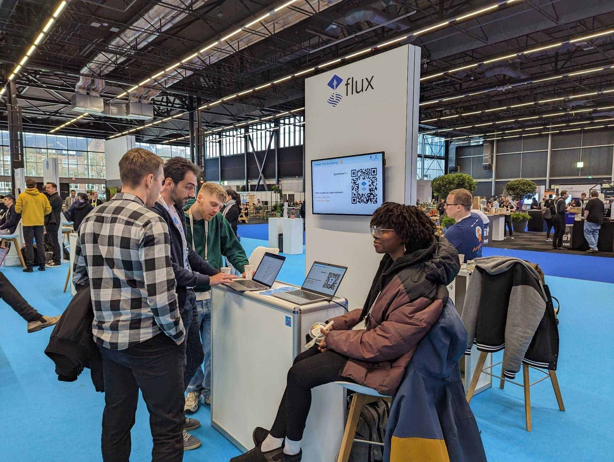 A gentleman showing tow other gentlemen the computer in flux booth with a lady on the side