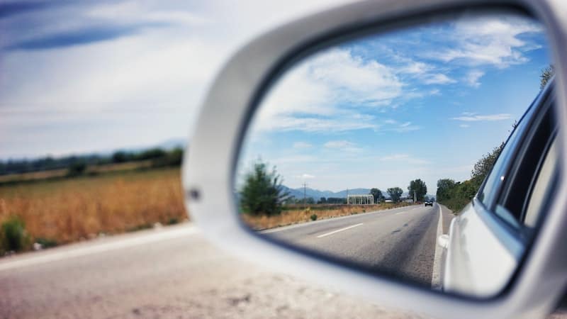 A road behind a car through a sideview mirror