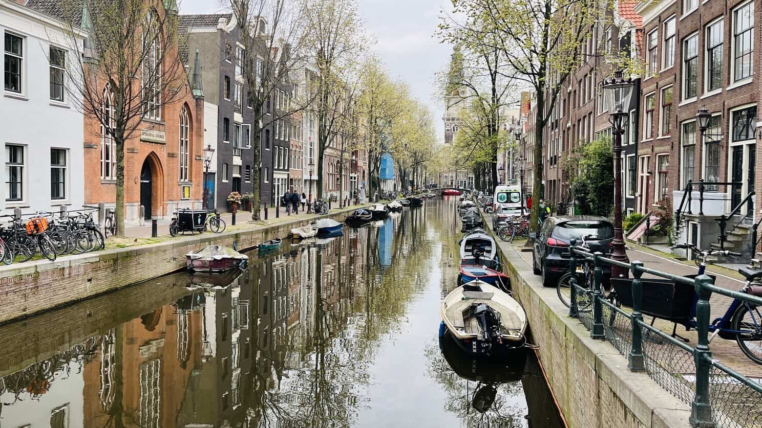 Buildings separated by river with small boats in Amsterdam
