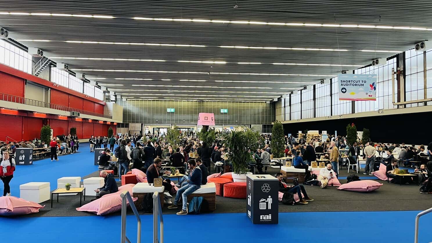 KubeCon + CloudNativeCon Europe 2023 Event Hall with people gathering around the booths or sitting on the beanbag