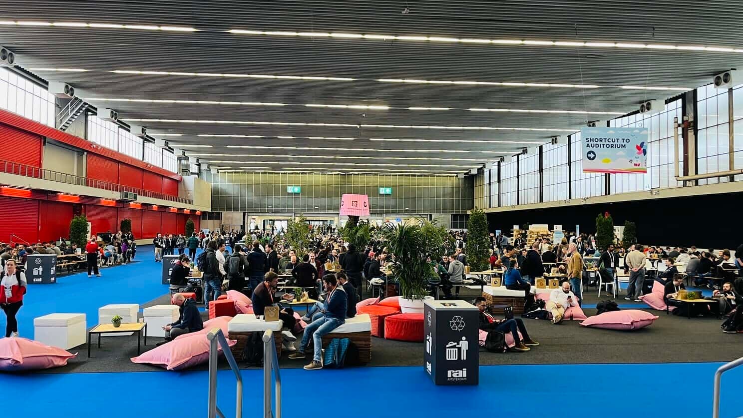 KubeCon + CloudNativeCon Europe 2023 Event Hall with people gathering around the booths or sitting on the beanbag