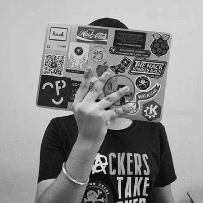 Karanjot Singh covering his face with Macbook full of stickers