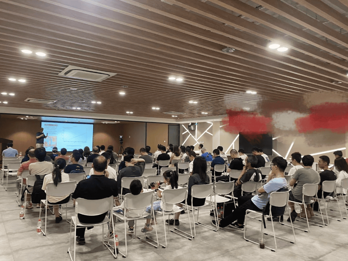 Participants including children in the event room paying attention to speaker  (Michael Yuan) presenting on the stage