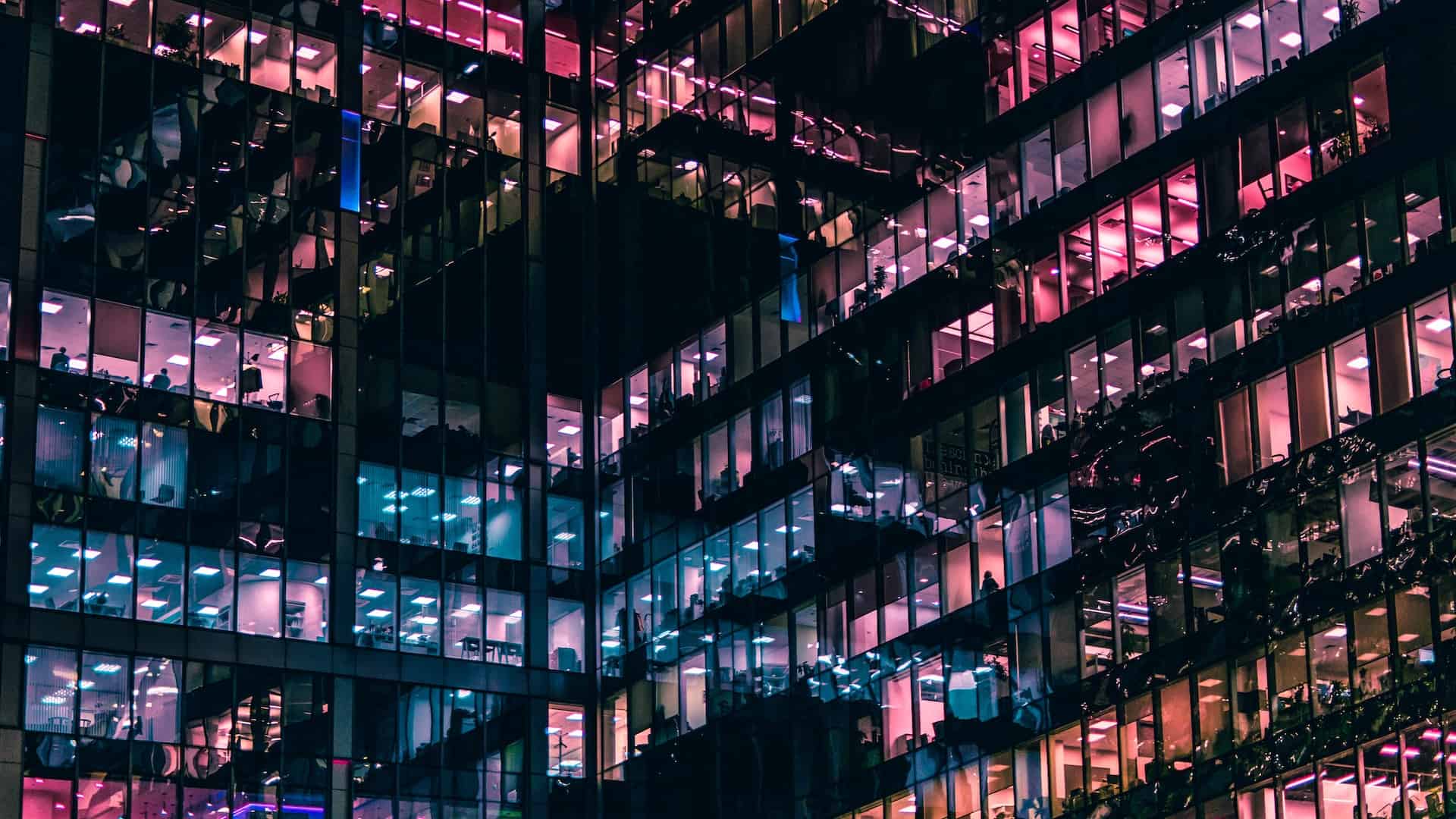 Image showing multiple glass offices illuminated by blue and pink lights