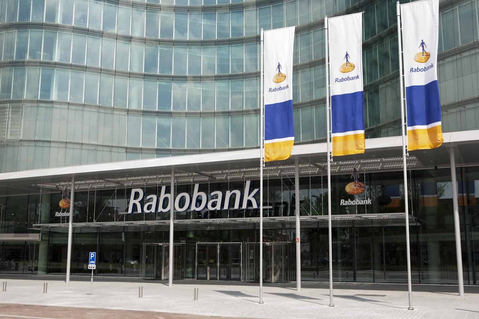 Photo of the front of the Rabobank headquarters, with branded flags flying by the main door