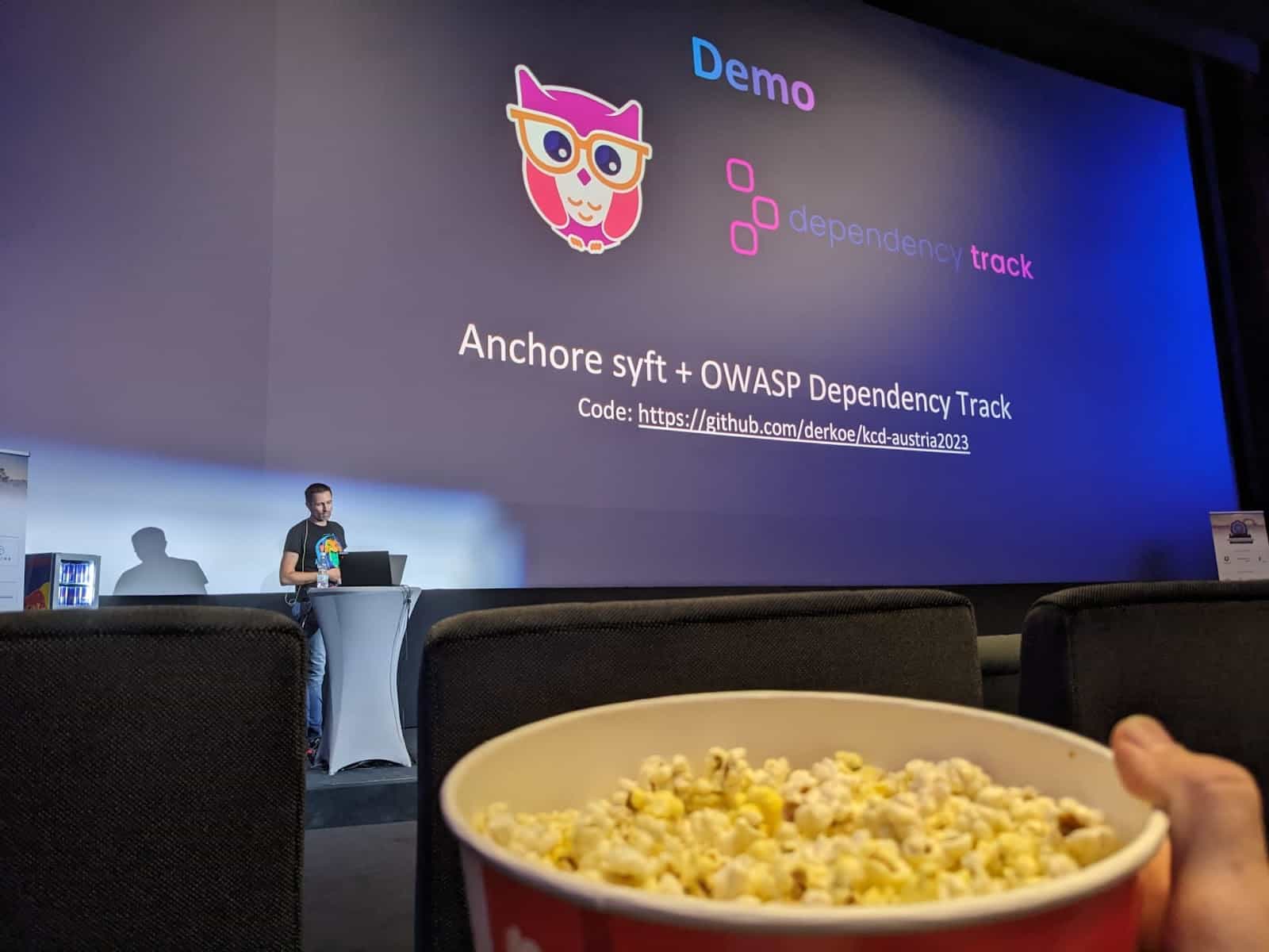 A person holding popcorn while listening to the talk Demo about Anchor syft + OWASP Dependency Track