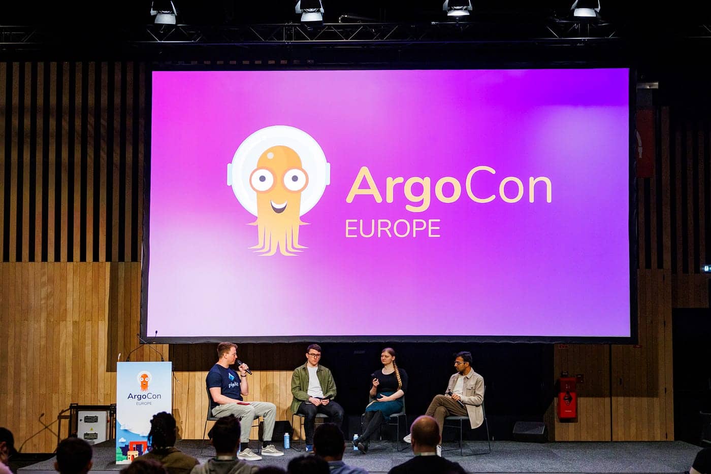 Four speakers on stage presenting ArgoCon Europe
