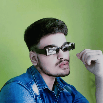 A profile image of Ronak, wearing black square sunglasses and a blue denim shirt, against a green backdrop. 
