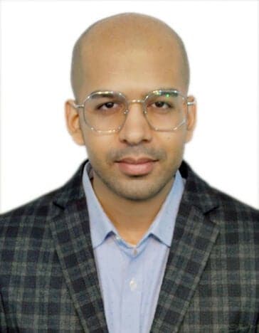 A profile image of Sparsh, wearing glasses, a check jacket and blue shirt, against a white backdrop.